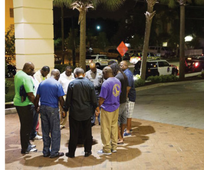 Worshipers gather to pray in a hotel parking lot across the street from the scene of the massacre. Credit: David Goldman, AP